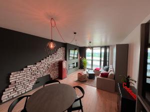 een woonkamer met een tafel en een bakstenen muur bij Industrial Apartment in Belval the University City in Esch-sur-Alzette