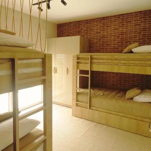 a room with two bunk beds and a brick wall at Casa Pipa Flamingos in Pipa