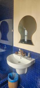 a bathroom with a white sink and a mirror at Hotel-Restaurant Le Kaouki in Sidi Kaouki
