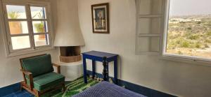 a room with a green chair and a window at Hotel-Restaurant Le Kaouki in Sidi Kaouki