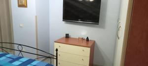 a bedroom with a dresser and a television on a wall at La casetta di samba in Anguillara Sabazia
