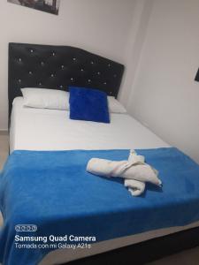 Una cama con una manta azul y toallas. en Apartamento Las Margaritas, en Santa Rosa de Cabal