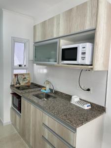 una pequeña cocina con fregadero y microondas en Regia Apartamentos Villa Sarita en Posadas