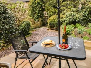 a table with a bottle of wine and a plate of food at Millward House in Longnor