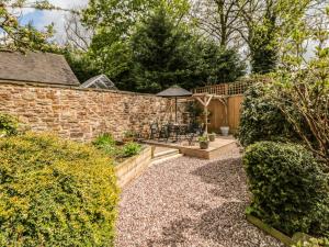 a garden with a stone wall and a table and chairs at Millward House in Longnor