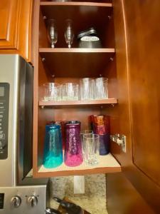 a cupboard with colorful glasses and bowls in it at Beachy Vibes + Game Day Fun on the Bay! in Tampa +48 photos