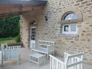 a patio with white chairs and a building at Manoir de la Chapelle in Condé-sur-Sarthe