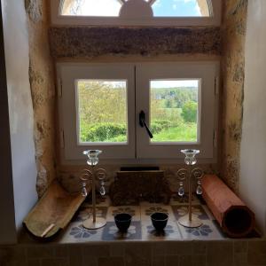 a room with two windows and a table with glasses at Manoir de la Chapelle in Condé-sur-Sarthe