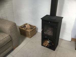 a stove in a living room with a couch and a basket at Garden View in Saxlingham Thorpe