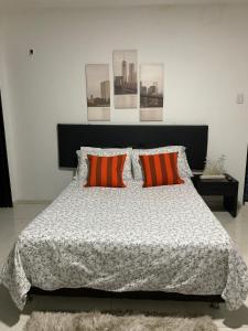 a bedroom with a bed with two orange pillows at El Rincón de Granada Hotel in Cali