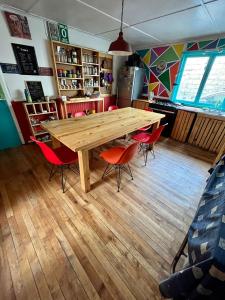 uma mesa de madeira num quarto com cadeiras vermelhas em Isla Yu Patagonia 2 em Puerto Natales