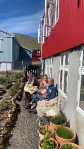 Un groupe de personnes assises à une table à l'extérieur d'un bâtiment dans l'établissement Heima í Stovu, à Hvalba