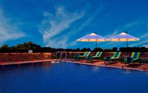 拉傑科德的住宿－Fortune Park JPS Grand, Rajkot - Member ITC's Hotel Group，游泳池畔的两把椅子和遮阳伞