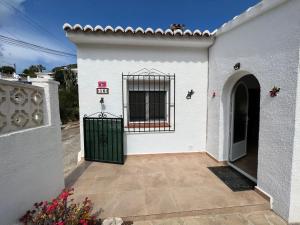 een wit huis met een poort en een deur bij Luces Del Mar Beautiful bungalow with seaview near to Moraira in Benitachell