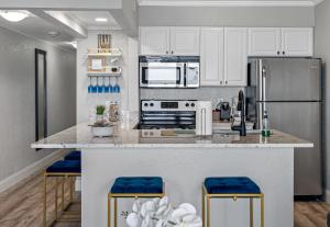 a kitchen with white cabinets and blue stools at Wake up to the ocean breeze - Enjoy amazing views in Tampa