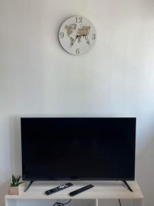 a clock on a white wall above a television at Appartement Calais Nord in Calais