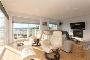 een woonkamer met witte stoelen en een open haard bij Luxury Lookout - Cable Bay Holiday Home in Cable Bay