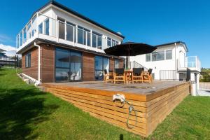 une maison avec une terrasse en bois et un parasol dans l'établissement Luxury Lookout - Cable Bay Holiday Home, à Cable Bay