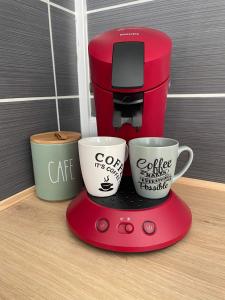 Appartement Calais Nord في كاليه: آلة صنع القهوة الحمراء مع كوبين قهوة عليها