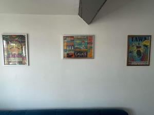 trois affiches sur un mur blanc avec un canapé bleu dans l'établissement Appartement Calais Nord, à Calais