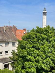 a lighthouse on top of a building next to a tree at Appartement Calais Nord in Calais