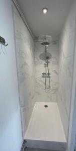 y baño con ducha y paredes de mármol blanco. en Appartement Calais Nord en Calais