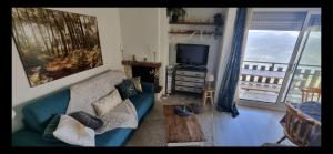 a living room with a couch and a television and a balcony at Refuge St Lary in Saint-Lary-Soulan