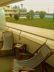 einen Balkon mit 2 Stühlen, einem Tisch und einem Fenster in der Unterkunft BEACH FRONT APARTMENT - with swimming pool, barbecue and tennis court! in Viana do Castelo