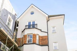a white house with a balcony on a street at Spacious, newly renovated, three bedroom TOWN CENTRE duplex apartment with free parking, sleeps seven - Walking distance to beach in Bournemouth