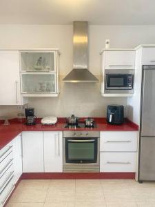 a kitchen with white cabinets and a red counter top at A cozy staying in the heart of Lanzarote. in San Bartolomé