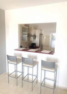 una cocina con 3 sillas de bar y una barra en A cozy staying in the heart of Lanzarote., en San Bartolomé