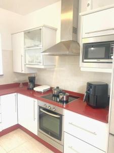 a kitchen with white cabinets and a red counter top at A cozy staying in the heart of Lanzarote. in San Bartolomé