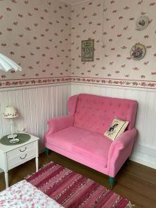 un sofá rosa en una esquina de una habitación en Strandbergs Stugor, en Mariehamn