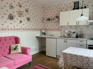 una cocina con una silla rosa y una mesa en Strandbergs Stugor, en Mariehamn