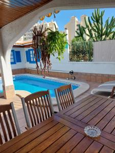 een houten tafel en stoelen naast een zwembad bij Beautiful Holiday Villa with heated private pool, Los Cristianos in Los Cristianos