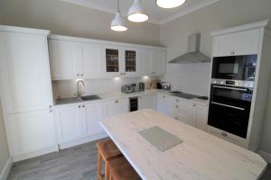 a kitchen with white cabinets and a table with chairs at Bakers Rest ideal for 2 families centrally located in Grasmere with walks from the door in Grasmere