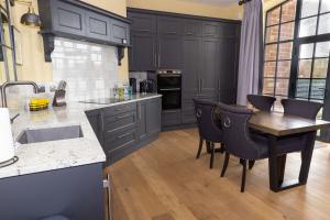 a kitchen with black cabinets and a wooden table and chairs at Tarn End Cottage with view to Talkin Tarn, near Lake District in Brampton +25 photos