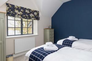 two beds in a bedroom with blue walls and a window at Tarn End Cottage with view to Talkin Tarn, near Lake District in Brampton