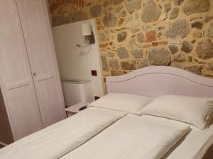 Cama blanca en habitación con pared de piedra en Residenza Tito Livio Teolo, en Teolo
