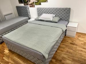 uma cama num quarto com uma cama cinzenta em KoTa apartmani Beograd em Karaburma