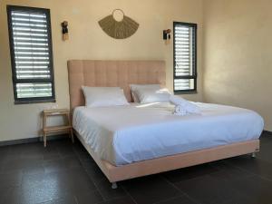 a large bed in a bedroom with two windows at בסנדלים: חאן בוטיק בגולן in Ma'ale Gamla