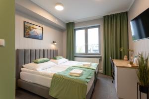 a hotel room with a bed and a desk and window at Apartamenty Albatros in Augustów
