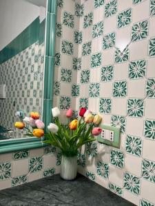 een vaas met bloemen in een badkamer met een betegelde muur bij POSITANO CENTRAL HOUSE free wi-fi and air condition in Positano