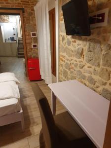 a living room with a white table and a tv on a stone wall at Residenza Tito Livio Teolo in Teolo