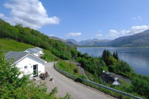 a house on the side of a road next to a lake at Old Springwell Croft in Onich