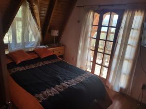 1 dormitorio con 1 cama y 2 ventanas grandes en Bungalow Villa Pehuenia en Villa Pehuenia