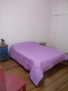 Cama morada en habitación con suelo de madera en Bienvenidos al Sur en Buenos Aires