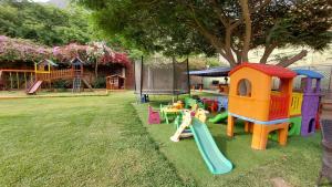 um quintal com um parque infantil com um escorrega e uma árvore em Huertalejandro Restaurante Campestre y Hospedaje em Cieneguilla