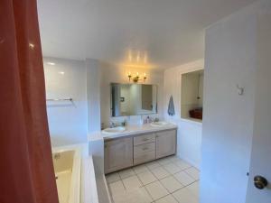 a white bathroom with two sinks and a mirror at Modern Apartment w/ Private Deck & BEAUTIFUL VIEWS in Topanga