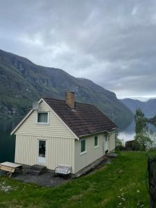 a white house on the side of a lake at Aurland Feriehus in Aurland